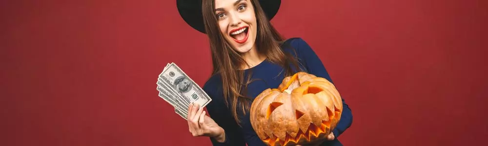 woman in witch hat holding pumpkin and money