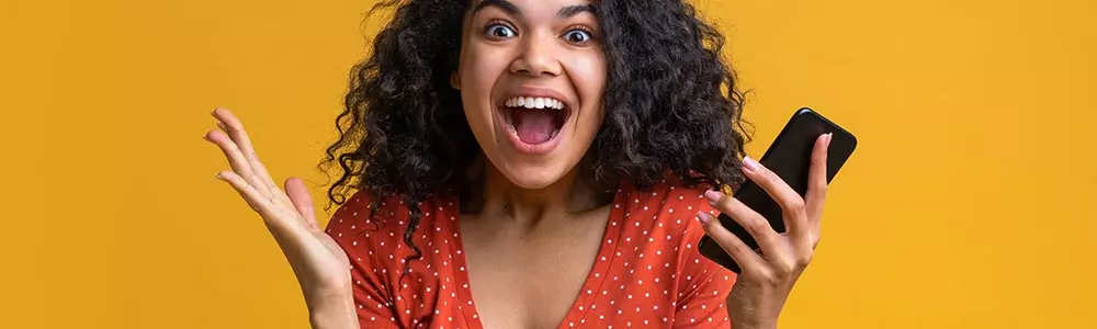 Young woman celebrating a big win on her phone