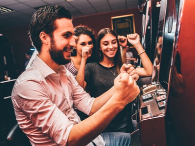 a bunch of friends cheering a win on an land-based slot machine